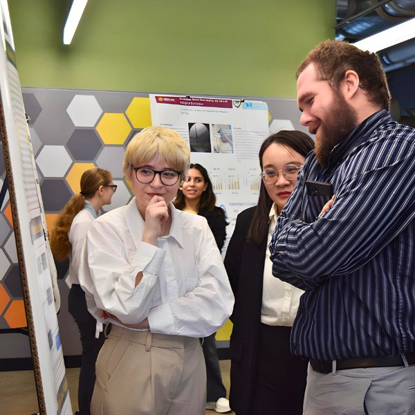 Students discuss a research poster at the 2023 CLAS Undergraduate Research Symposium