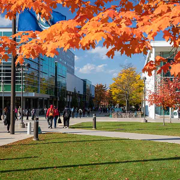 The center of campus with students walking and fall colored leaves on the trees